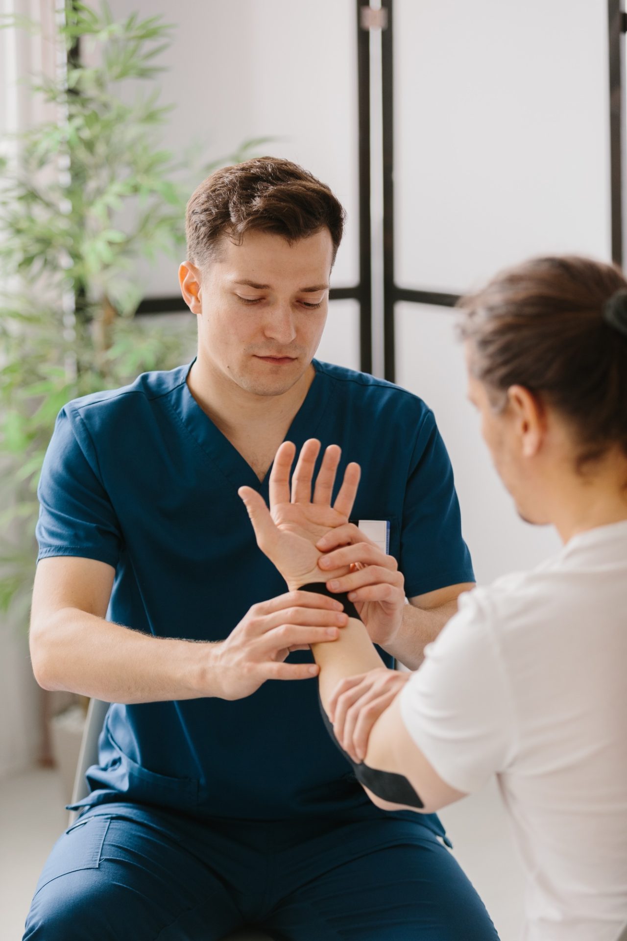 Orthopedic doctor applying kinesiology tape on a patient's arm.